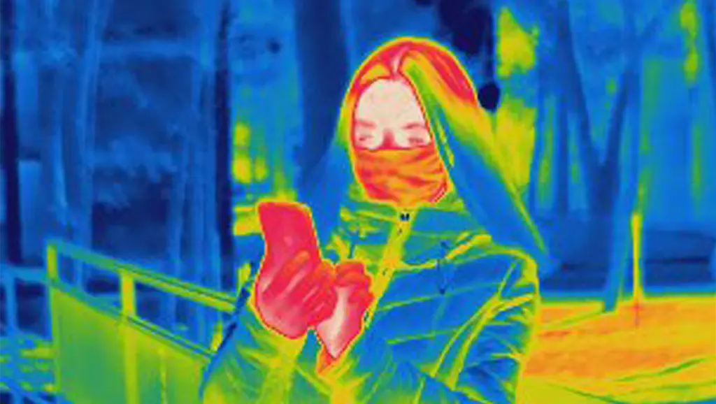 Infrared effect picture with a woman holding a cell phone and radiation flowing from the device to her body.