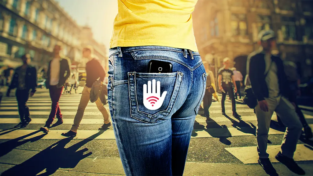 A woman is wearing tight jeans with a cell phone popping out of the back pocket. The pocket has the WaveLess logo, which includes a palm stand with wifi symbol in the middle, implying that it stops radiation.